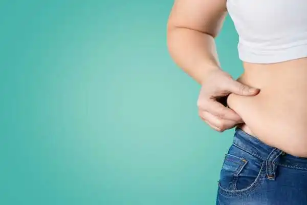 Image of woman pinching her love handles to show weight gain Cannock